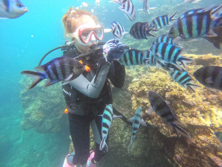 ダイビングで魚に囲まれる女性